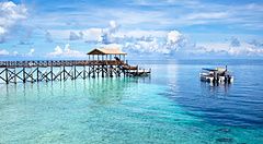 Molo di legno e barca su acque cristalline a Sipadan Island, Malesia.