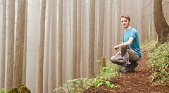 Persona accovacciata in una foresta nebbiosa sul Monte Mitake.