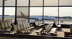 Veduta interna di una sala d'attesa all'aeroporto di Narita con un aereo Eva Air visibile attraverso una grande vetrata.