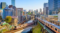 Treni attraversano il fiume Kanda a Ochanomizu, Tokyo con edifici moderni.
