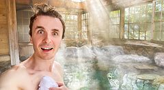 Marco Togni sorridente in un onsen a Yufuin con luce solare e vapore