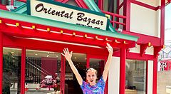 Marco Togni in piedi davanti all'ingresso rosso dell'Oriental Bazaar a Tokyo con le braccia sollevate.