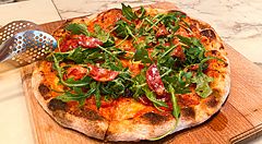 Una pizza con salame e rucola su un tagliere di legno al The Pizza Bar On 38th nel Mandarin Oriental Hotel di Tokyo.