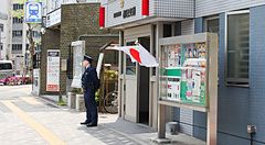 Poliziotto in piedi davanti a un koban in Giappone con bandiera giapponese.