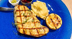 Un piatto con pollo a Sizzler grigliato, purè di patate e limone su un tavolo di legno nel ristorante Sizzler.