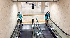 due addetti puliscono le scale mobili in uno spazio pubblico.
