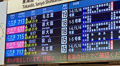 Un tabellone informativo in una stazione mostra treni Shinkansen in ritardo.
