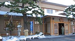 Facciata innevata del ryokan Ichinomatsu a Hakodate con una persona all'ingresso.