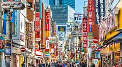 Shibuya Cener-gai a Tokyo con folla e insegne colorate di giorno.