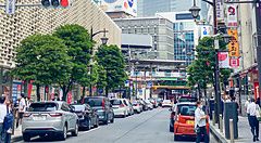 Una strada urbana a Shimbashi con il New Shinbashi Building sulla sinistra e vari edifici commerciali.