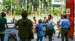 Gruppo di persone in una smoking area in Giappone, alcune fumano.