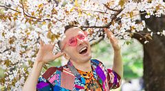 Marco Togni sorridente sotto un albero di ciliegio in fiore a Tokyo.