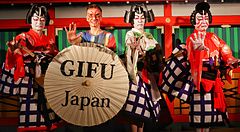 Persone in costumi tradizionali giapponesi posano con un grande ombrello a Gifu.