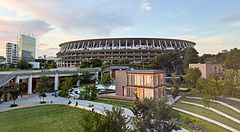 Lo Stadio nazionale del Giappone a Tokyo circondato dal verde di un parco urbano al tramonto.