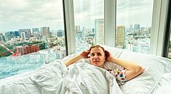 Marco Togni è a letto in una corner room dell'InterContinental the Strings Tokyo con vista panoramica sullo skyline urbano.