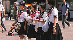 Gruppo di studentesse in uniforme cammina per strada in giappone.