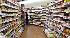 Corridoio di un supermercato Seijo Ishii in Giappone con scaffali colmi di prodotti alimentari e una persona.