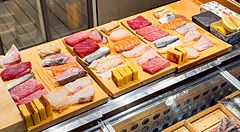 Pesce crudo tagliato su vassoi di legno, pronto per fare sushi.