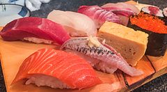 Un assortimento di nigiri e gunkan sushi servito su un tagliere di legno al ristorante Sushidokoro Okame a Tokyo.