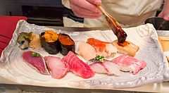 Uno chef prepara del sushi spennellando salsa su un pezzo di pesce presso il ristorante Sushimaru a Shinjuku.