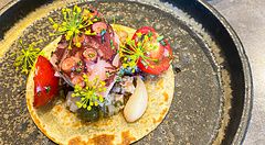 Taco morbido con polpo, pomodorini e capperi, servito accanto a un secondo di carne al ristorante Ode di Tokyo.