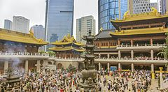 Folla di fedeli nel tempio buddhista Jing'an a Shanghai tra moderni grattacieli.