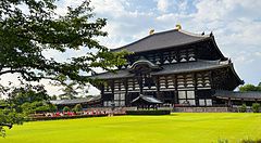 Il Tempio Todai-ji si erge maestoso dietro un prato verde con persone che camminano nel parco di Nara.