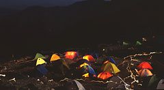Tende colorate illuminate di notte con il monte Fuji sullo sfondo.