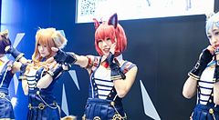 Tre persone indossano costumi da cosplay ispirati ad anime con orecchie da animale durante la Tokyo Anime Fair.