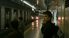 Una banchina della metropolitana a Tokyo con Marco Togni in primo piano e un treno che arriva in stazione.