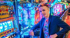 Marco Togni seduto davanti a macchine pachinko luminose in Giappone.