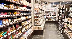 Interno del negozio Tomizawa Shoten a Machida, con scaffali in legno pieni di prodotti alimentari e da pasticceria.