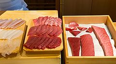 Diversi tagli di tonno esposti su piatti a Sushi Masashi.
