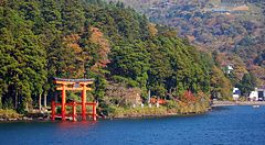 Un torii rosso sul Lago Ashi in Giappone, circondato da alberi.