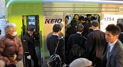 Persone in abiti formali salgono su un treno della linea Keio in Giappone.