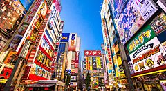 Strada colorata di Akihabara, Tokyo, con cartelloni di anime e tecnologia.