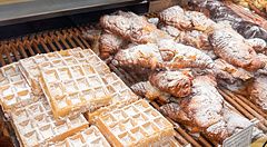 Vetrina di una panetteria Paul in Giappone con waffle al cocco e croissant cosparsi di zucchero a velo.