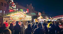 Veduta serale del Yokohama Red Brick Christmas Market con persone in coda davanti a chioschi decorati a tema natalizio.