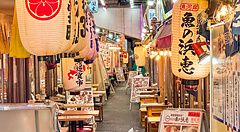 Veduta interna del vicolo Yurakucho Yokocho a Tokyo, caratterizzato da numerose lanterne di carta e insegne luminose.