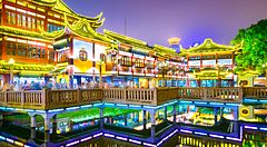 Edifici illuminati a Yuyuan Gardens di Shanghai riflessi nell'acqua.