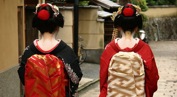 Due donne maiko in kimono camminano per una strada a Kyoto.