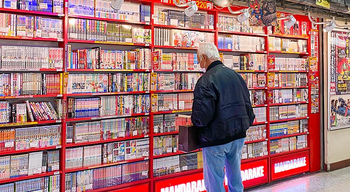 Un uomo guarda gli scaffali pieni di manga nel negozio Mandarake, decorato con copertine di fumetti vintage.