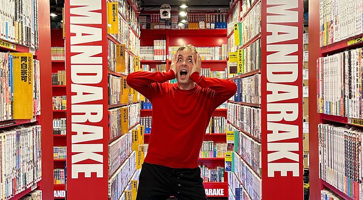 Persona in maglia rossa tra scaffali di manga a Mandarake.