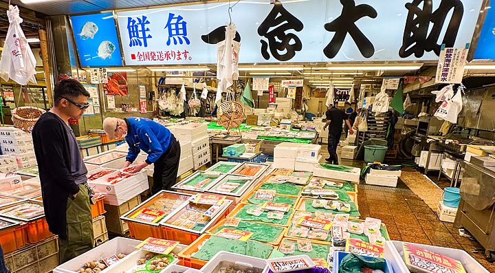 Scene al Mercato Omicho di Kanazawa con pesce fresco e venditori.