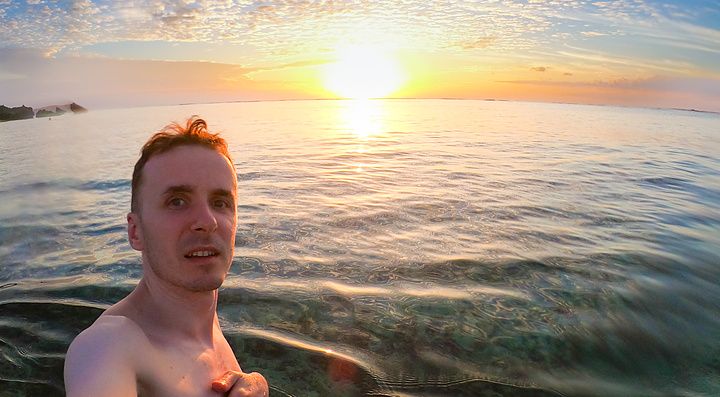 Marco Togni scatta un selfie immerso nel mare al tramonto presso la spiaggia Mimikiri Beach a Okinawa.