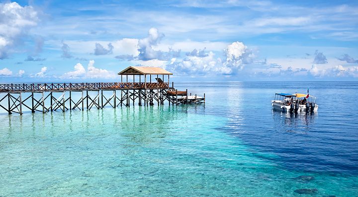 Molo di legno e barca su acque cristalline a Sipadan Island, Malesia.