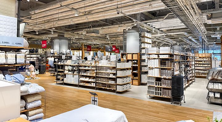 Veduta interna del negozio Muji a Tokyo con scaffalature in metallo, articoli per la casa e soffitto industriale.