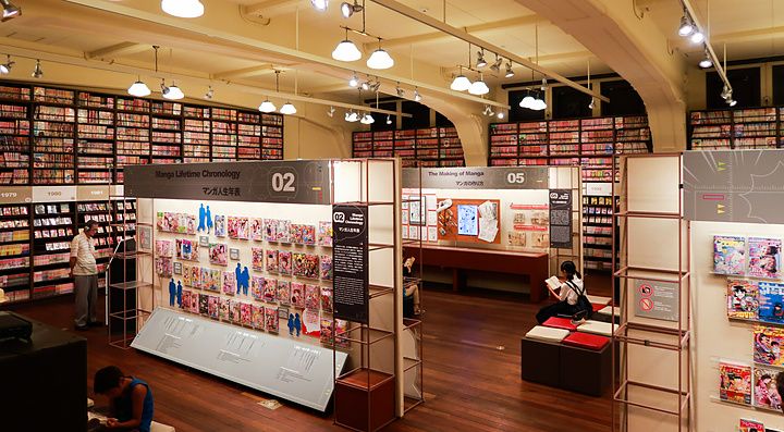 Interno del Museo di Manga a Kyoto con persone che esplorano la collezione di manga.