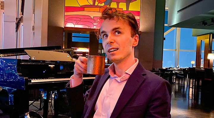 Marco Togni siede all'interno del New York Bar del Park Hyatt Hotel a Tokyo, tenendo in mano una tazza metallica.