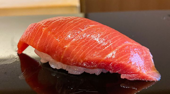 Un nigiri di chutoro posato su una superficie lucida scura da Sushi Masashi a Tokyo.